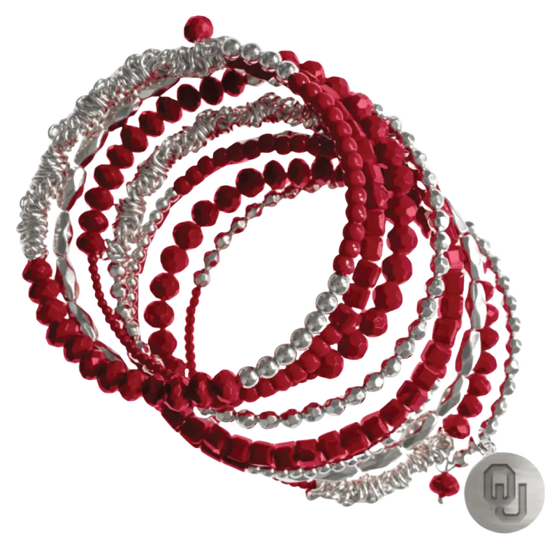 Crimson, silver, and sparkle — this school-color stunner stacks the style while you rep OU loud and proud. With a silver OU charm and playful beaded layers, it’s the perfect game-day glam to shine at tailgates, in the stands, or wherever you cheer. Lightweight, bold, and Sooner strong — because winning looks good on you!