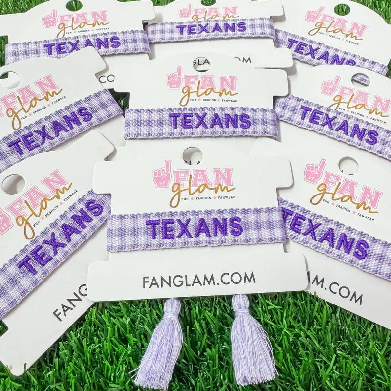 Bleed Purple and Stand Tall wearing our Tarleton Texans Tassel Bracelet! Featuring bold TEXANS embroidery on a chic purple and white gingham woven band, this adjustable bracelet is perfect for game days, tailgates, and showing off your Texan pride.

With stylish tassel accents, it’s the perfect accessory for any true Tarleton State fan. Go Texans!