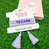 "Bleed Purple and Stand Tall with this Tarleton Texans Tassel Bracelet! Featuring bold ‘TEXANS’ embroidery on a chic purple and white woven band, this adjustable bracelet is perfect for game days, tailgates, and showing off your Texan pride. With stylish tassel accents, it’s the perfect accessory for any true Tarleton State fan. Go Texans!"