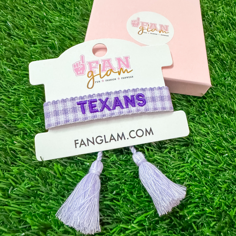 "Bleed Purple and Stand Tall with this Tarleton Texans Tassel Bracelet! Featuring bold ‘TEXANS’ embroidery on a chic purple and white woven band, this adjustable bracelet is perfect for game days, tailgates, and showing off your Texan pride. With stylish tassel accents, it’s the perfect accessory for any true Tarleton State fan. Go Texans!"