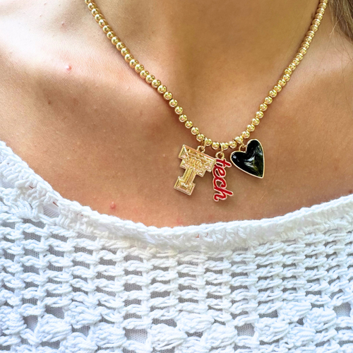 Show off your Red Raider pride in style with our Texas Tech Red Raider Gold Ball Beaded Charm Necklace! This statement piece combines bold team spirit with a fashion-forward edge. Perfect for game days, tailgates, or anytime you want to add a touch of glam to your look.&nbsp;