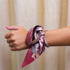 This vibrant scarflette is full of College Station charm and a whole lotta Aggie spirit! Featuring delicate florals in bold maroon and soft blush, it's sprinkled with playful pup silhouettes — a sweet nod to everyone's favorite mascot. Whether you're walking campus, heading to Kyle Field, or brunching on Northgate, this silky stunner is your new game day (and every day) essential.