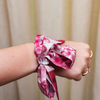 Calling all Razorback sweethearts!&nbsp;This Fayetteville-inspired scarflette is full of southern charm and hometown pride. With a soft floral pattern in shades of red and blush and adorable hog silhouettes tucked in the design, it’s a playful nod to everything we love about life on The Hill. Whether you’re strolling Dickson Street, tailgating at Donald W., or cheering&nbsp;Wooo Pig Sooie! with your crew, this silky little accessory brings the perfect pop of Fayetteville flair.