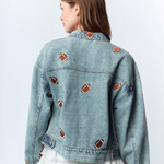 Get ready to steal the spotlight this tailgate season with the Friday Night Lights Football Embroidered Denim Jacket. Its light wash and relaxed, slightly oversized fit make it perfect for layering on cool fall evenings. Fully covered in playful football embroidery, it adds a fun, sporty vibe to any look. Whether layered over your favorite tees, dresses, or team colors, this jacket is your go-to for game day style and comfort.