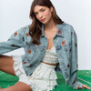 Get ready to steal the spotlight this tailgate season with the Friday Night Lights Football Embroidered Denim Jacket. Its light wash and relaxed, slightly oversized fit make it perfect for layering on cool fall evenings. Fully covered in playful football embroidery, it adds a fun, sporty vibe to any look. Whether layered over your favorite tees, dresses, or team colors, this jacket is your go-to for game day style and comfort.