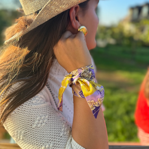Geaux glam, Tiger style! This LSU-inspired scarflette is loud, proud, and full of Southern sparkle! Featuring a chic floral print in purple and gold with playful tiger silhouettes woven throughout, it's the perfect mix of fierce and feminine. Whether you're tailgating in Baton Rouge, walking to class on campus, or chanting Geaux Tigers! at the top of your lungs, this silky stunner brings big LSU energy to any outfit.