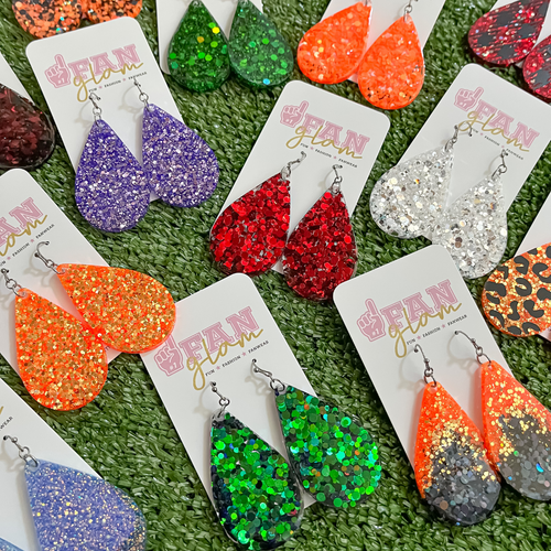 Our GameDay Glitter Glam Dangle earrings are the perfect combination of bright colors and fun prints!   Available in an array of team colors, you can pick and choose your favorite print, shape and design to elevate your GameDay glam. 