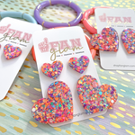 Love Is In The Air...  And our Glitter Glam Mini Heart Studs are the perfect pop of color + glam to help spread love to all your favorite humans this Valentine's!    A perfect gift for your bestie or your little one, its a versatile size that all ages can enjoy!  Super lightweight and comfortable, you will forget you have them on.