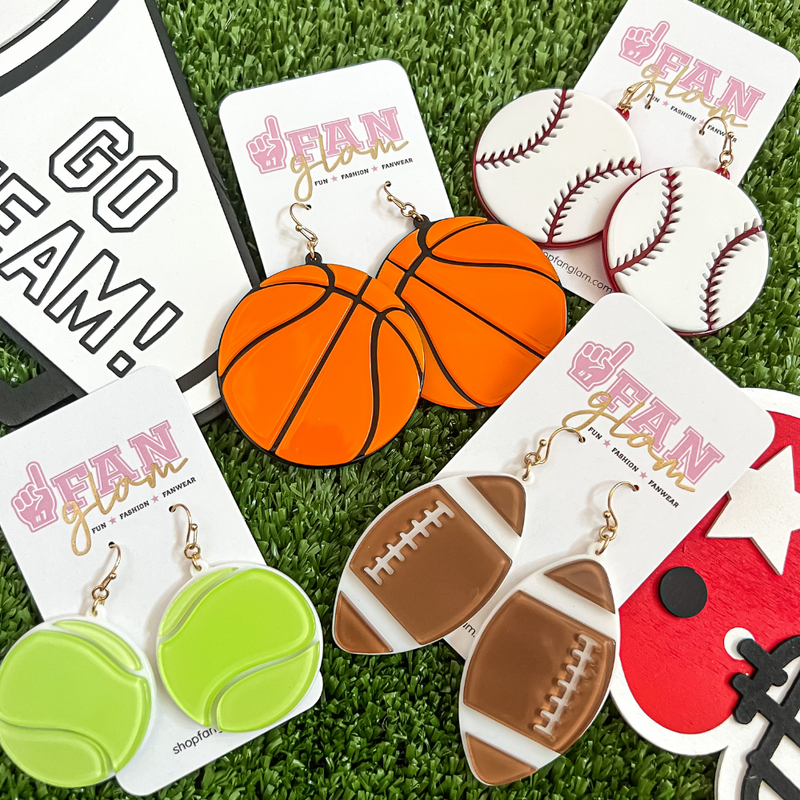 Show your love for the game when accessorizing your Game Day look with our sporty + chic acrylic dangle sports ball earrings.    Available in four sports options:  Basketball, Football, Tennis, and Baseball 